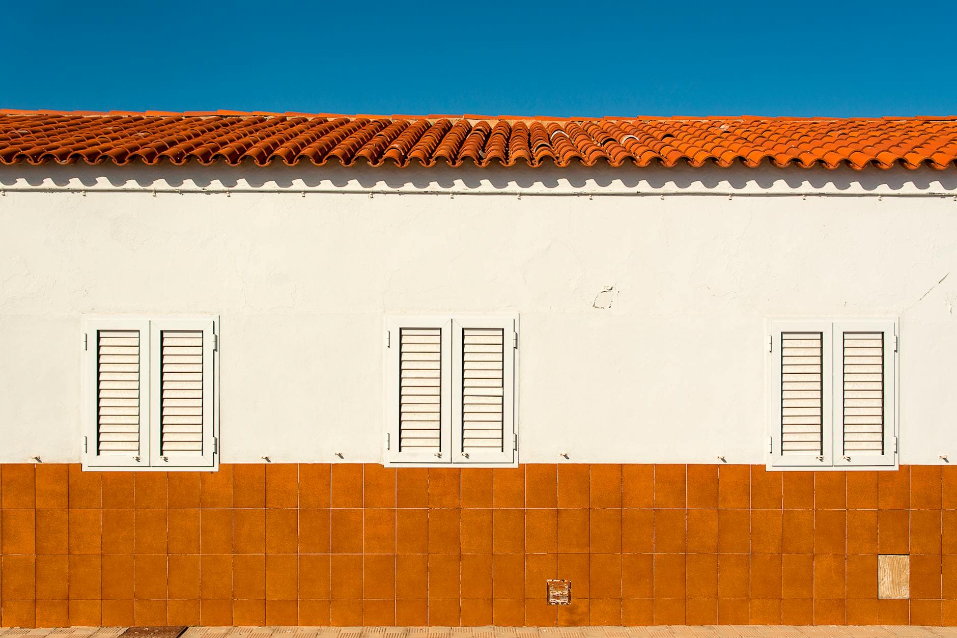 Vivienda mediterránea con ventanas y contraventanas blancas bajo cielo despejado